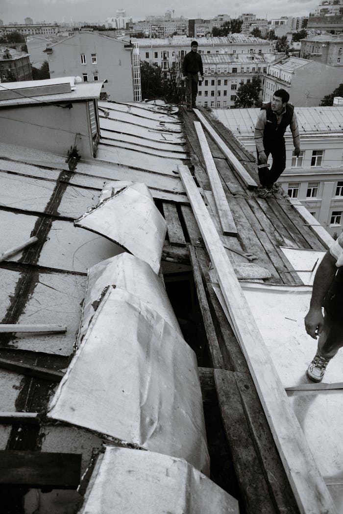 Builders mending old weathered roof in town